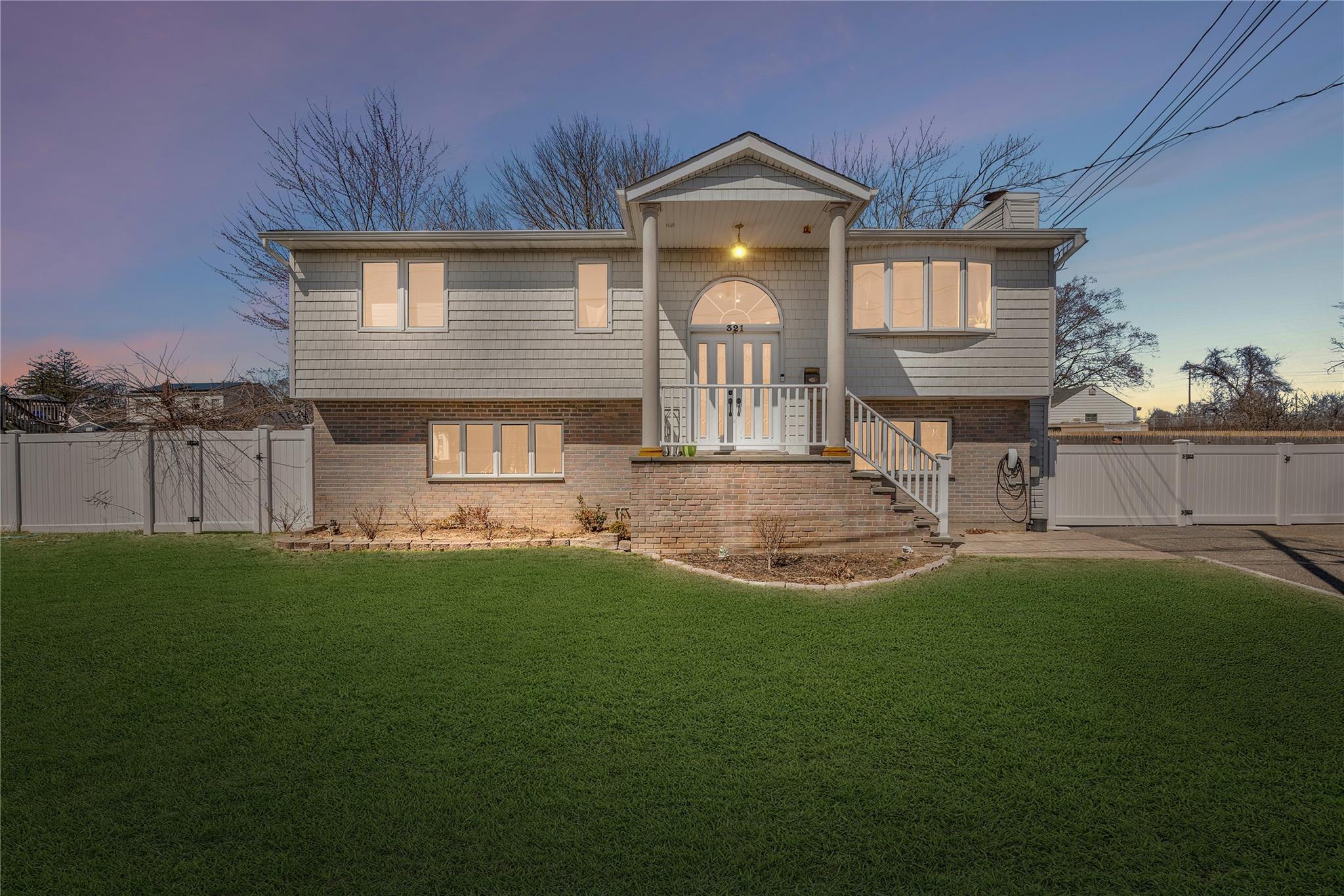 Raised ranch featuring a gate, a lawn, and brick siding