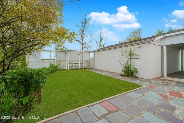 a view of a backyard with plants and a large tree