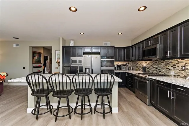 a kitchen with stainless steel appliances granite countertop a kitchen island hardwood floor and a sink