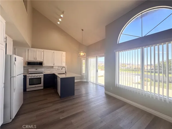 a large white open kitchen with cabinets and wooden floor