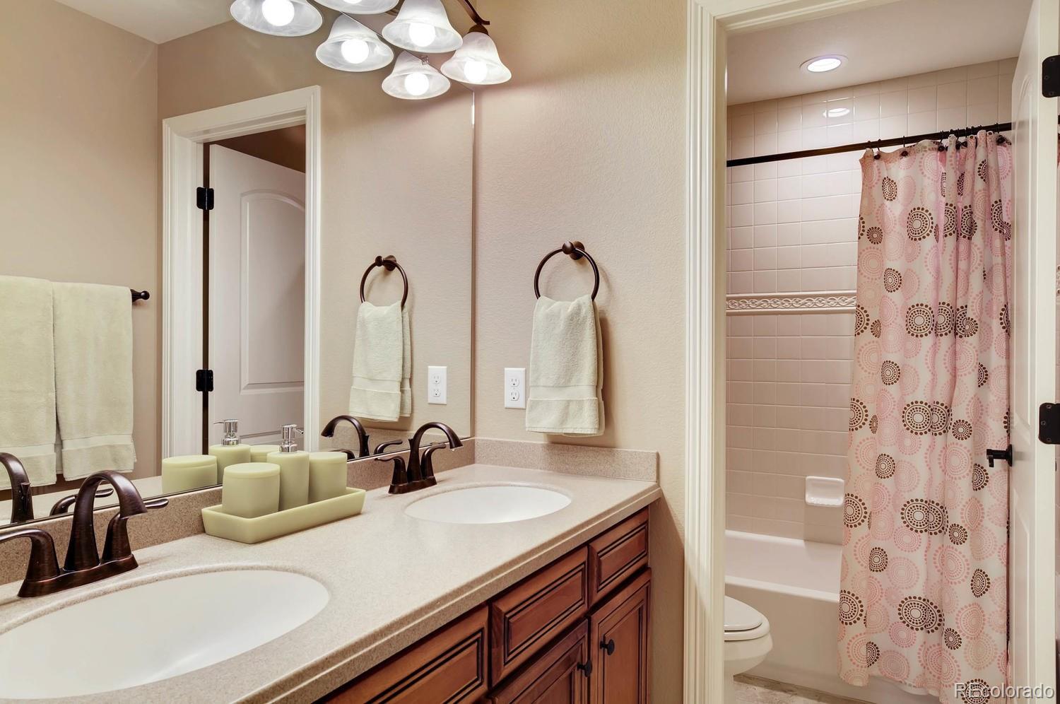 10560 Sundial Rim Road Highlands Ranch, CO 80126 - Photo 18 of 27 a bathroom with double vanity sinks a toilet a mirror and shower