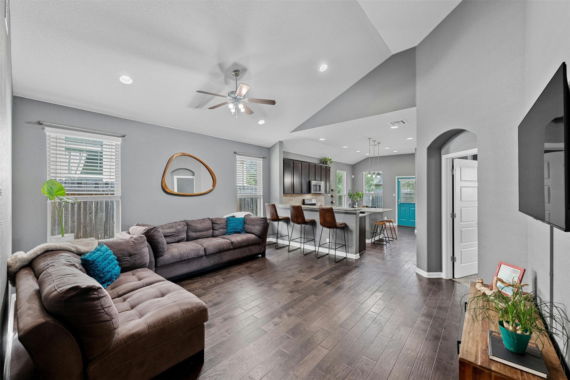 Natural light pours in through large windows, enhancing the warmth of the hardwood flooring.
