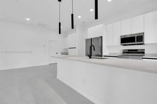 a kitchen with stainless steel appliances kitchen island sink refrigerator and microwave