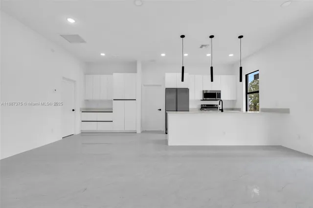 a view of kitchen with white cabinets and stainless steel appliances