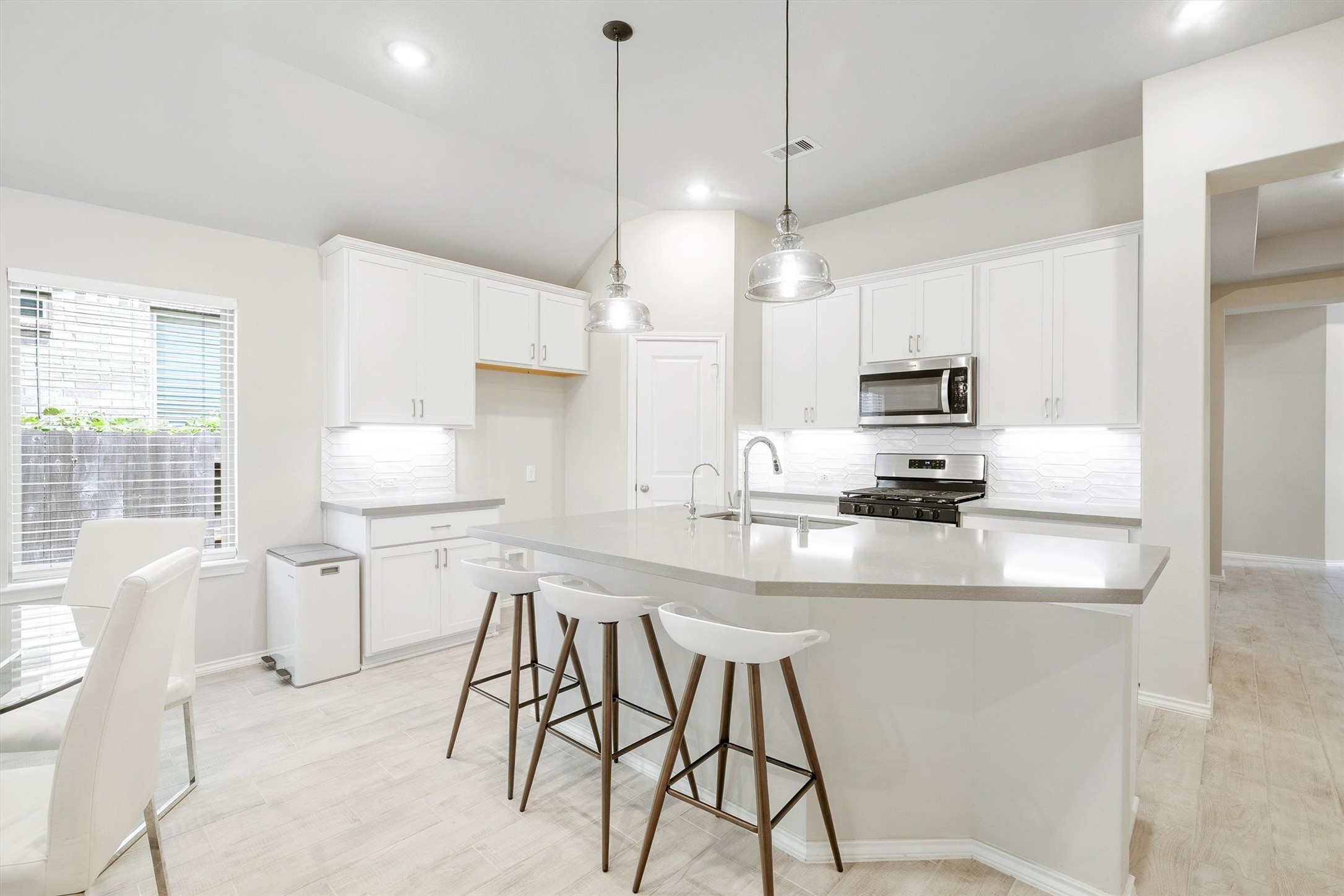 17270 Wild Watermelon Way Conroe, TX 77302 - Photo 6 of 28 White shaker cabinets, Omega Stone countertops, a gas range, stainless steel appliances, and pendant lights over the island that make this kitchen as good-looking as it is functional. The breakfast bar seating and pantry access make it the kind of kitchen you actually want to cook in.
