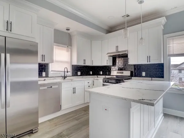 a kitchen with stainless steel appliances granite countertop a refrigerator a sink dishwasher a stove and white cabinets with wooden floor