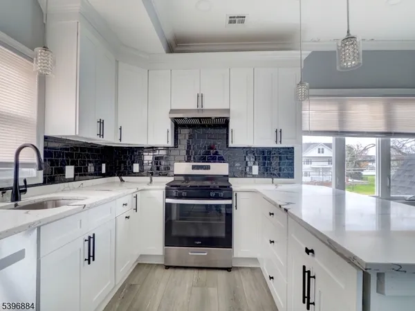 a kitchen with stainless steel appliances granite countertop a stove a sink and a white cabinets