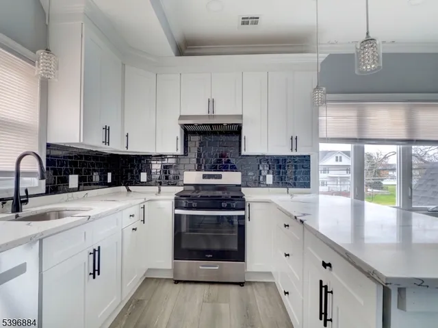 a kitchen with stainless steel appliances granite countertop a stove a sink and a white cabinets