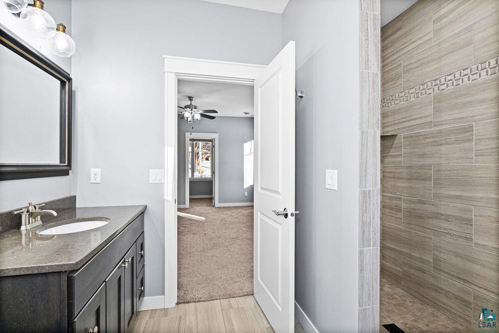 3879 Okerstrom Road Hermantown, MN 55811 - Photo 17 of 32 Bathroom with vanity, a walk in shower, light wood-style flooring, light colored carpet, and ceiling fan