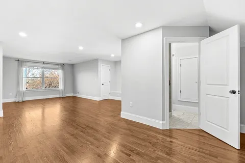an empty room with wooden floor and window