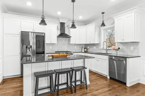 a kitchen with stainless steel appliances granite countertop a sink refrigerator a stove a center island and wooden floor