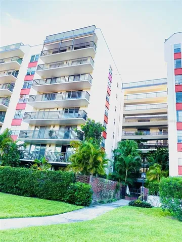 a front view of a multi story residential apartment building with yard and entertaining space