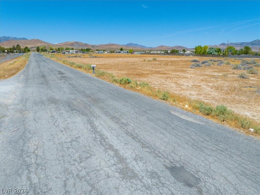 4580 Lawrence Road Pahrump, NV 89048 - Photo 7 of 40 A long, clear road extends through a desert landscape towards distant mountains.