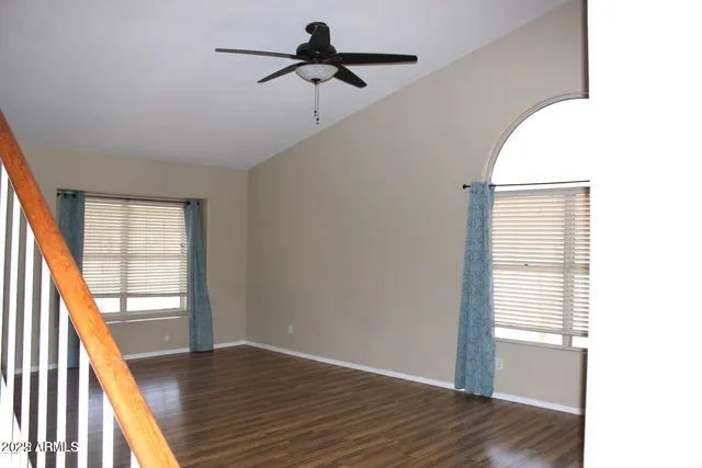 a view of empty room with wooden floor and fan