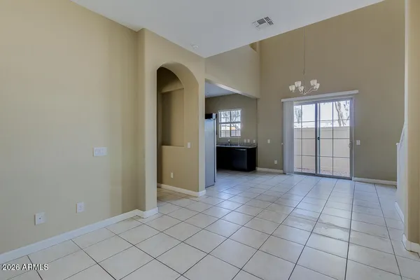 an empty room with windows and way to kitchen