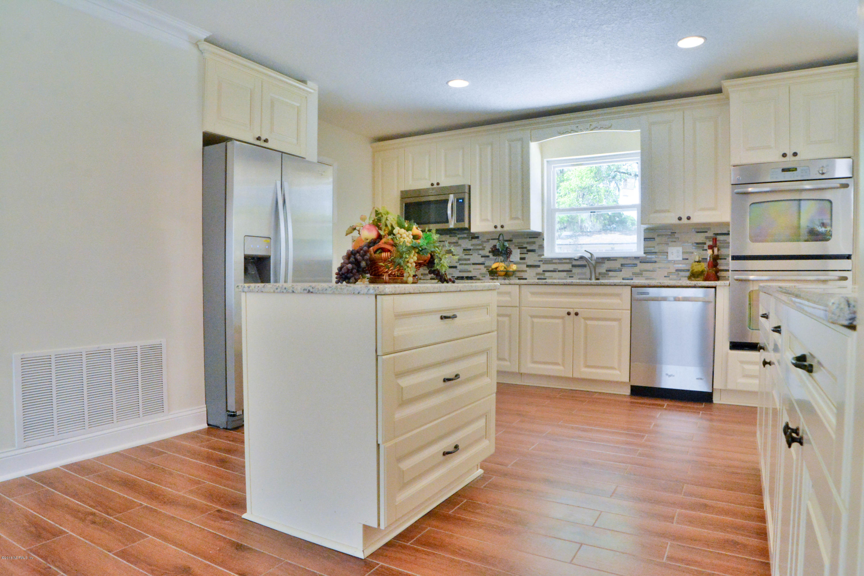 6717 West Fincannon Road Jacksonville, FL 32277 - Photo 11 of 32 a kitchen with stainless steel appliances granite countertop a refrigerator a sink dishwasher a stove and white countertops with wooden floor