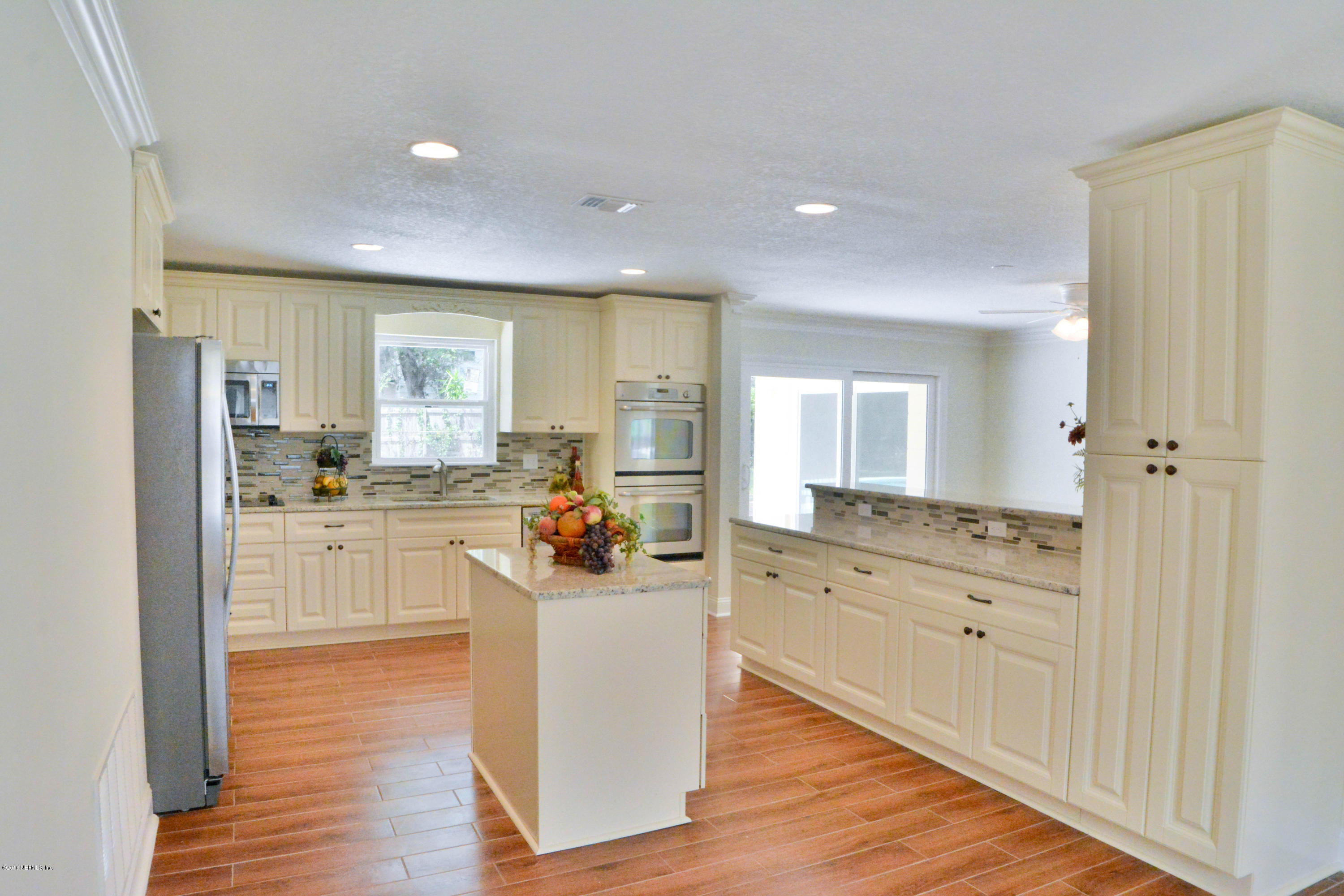 6717 West Fincannon Road Jacksonville, FL 32277 - Photo 12 of 32 a kitchen with white cabinets and wooden floor