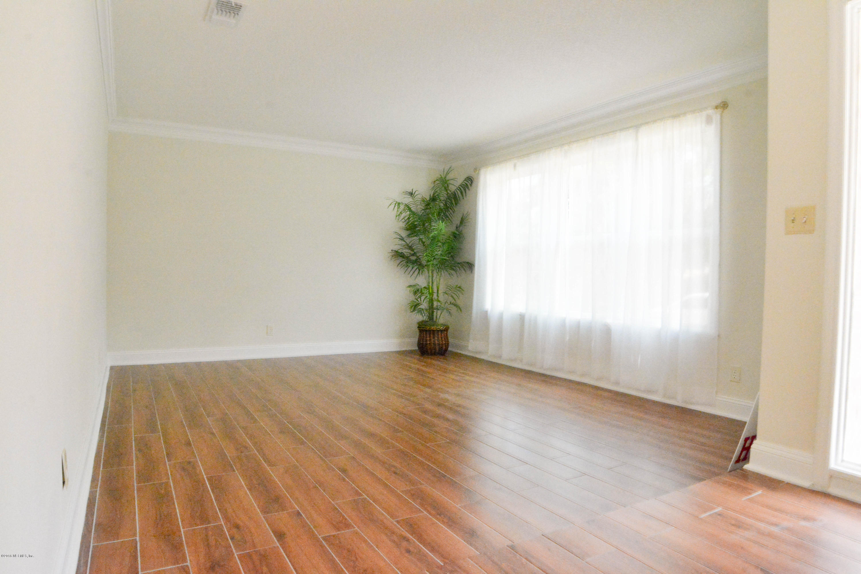 6717 West Fincannon Road Jacksonville, FL 32277 - Photo 6 of 32 an empty room with wooden floor and windows