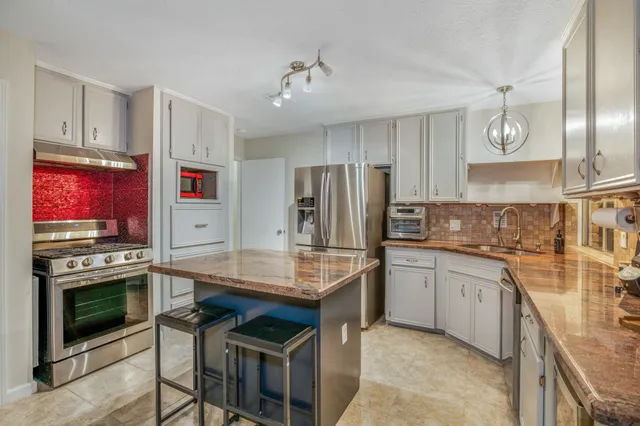 a kitchen with kitchen island granite countertop a stove oven and sink