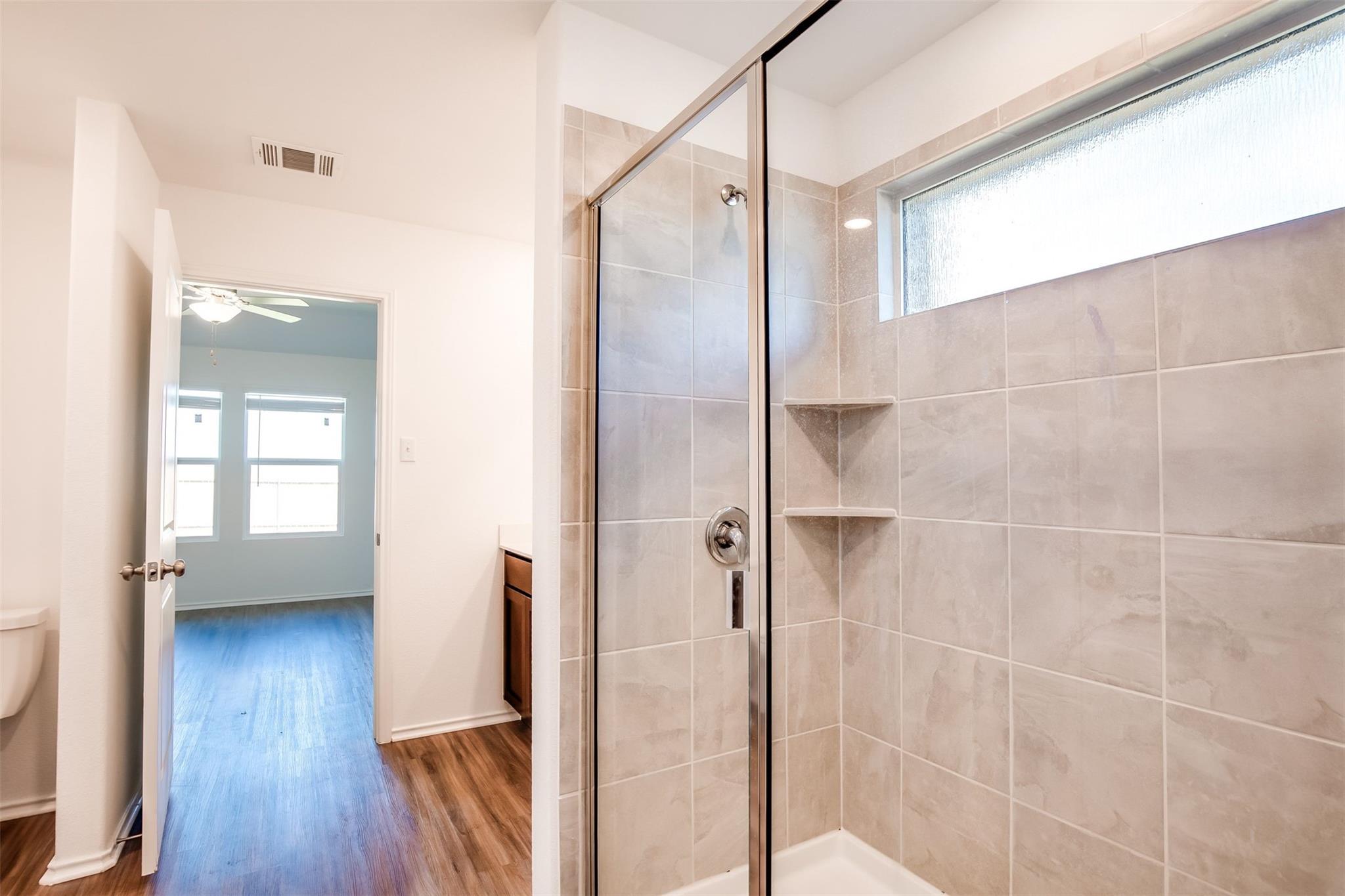 614 Milliner Loop Hutto, TX 78634 - Photo 11 of 25 Tiled shower with glass enclosure in a well-appointed bathroom.