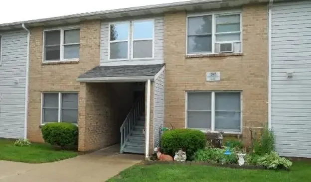 a view of a brick house with a yard potted plants and a large window