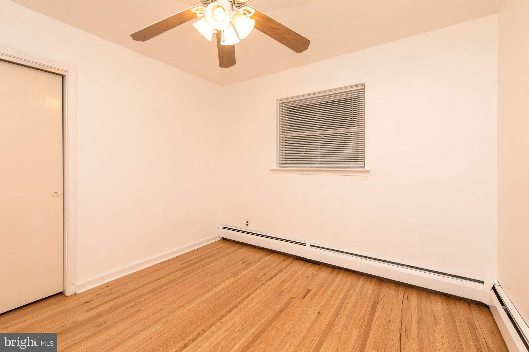 95 Radburn Road Huntingdon Valley, PA 19006 - Photo 24 of 40 an empty room with wooden floor chandelier fan and windows