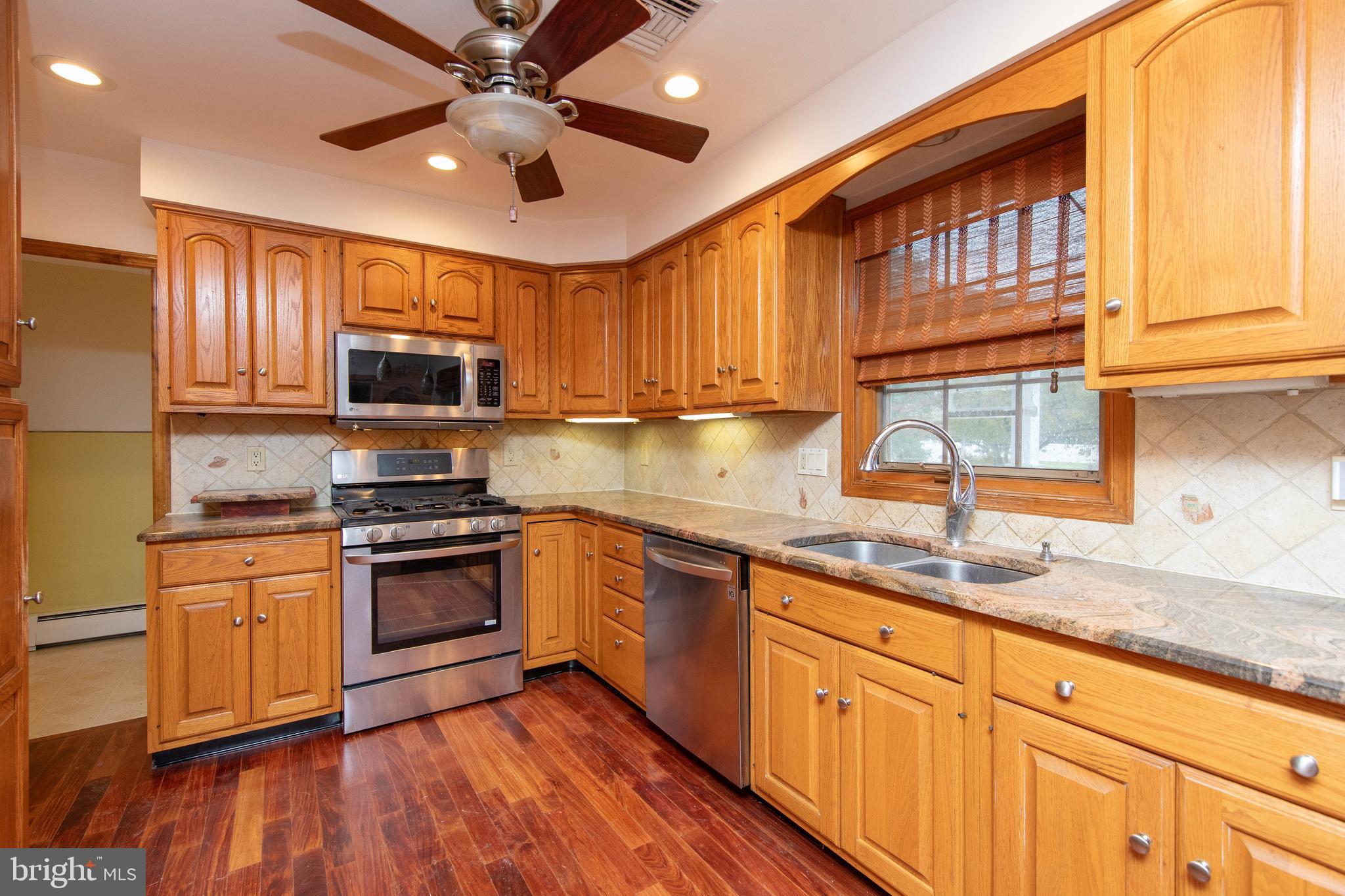95 Radburn Road Huntingdon Valley, PA 19006 - Photo 7 of 40 a kitchen with stainless steel appliances granite countertop wooden cabinets a sink a stove a refrigerator and island with wooden floors