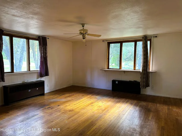 a view of an empty room with wooden floor and a window