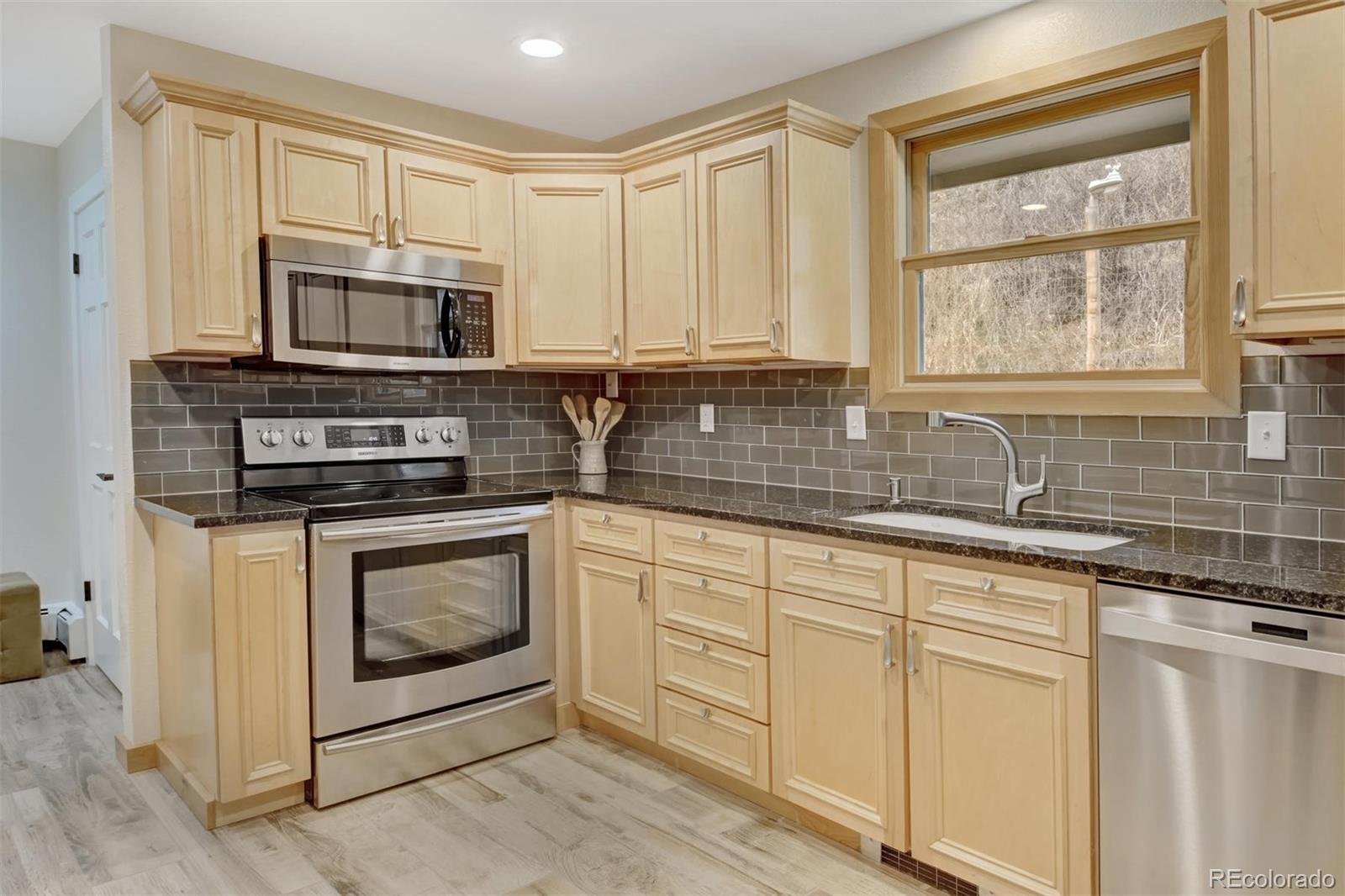 6761 Olde Stage Road Boulder, CO 80302 - Photo 11 of 36 a kitchen with stainless steel appliances granite countertop white cabinets a sink a stove a microwave and island