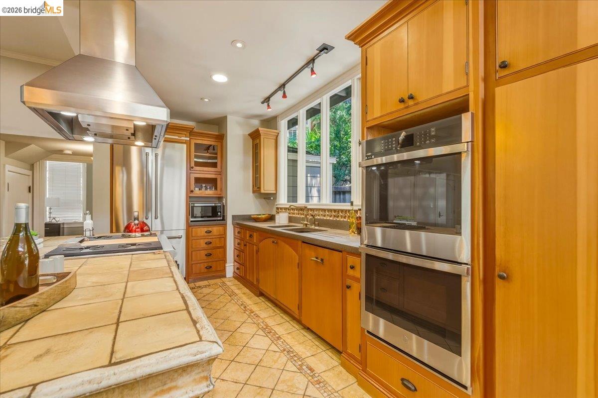 1631 La Vereda Road Berkeley, CA 94709 - Photo 10 of 42 Kitchen featuring wood cabinetry, stainless steel appliances, and a tiled countertop island