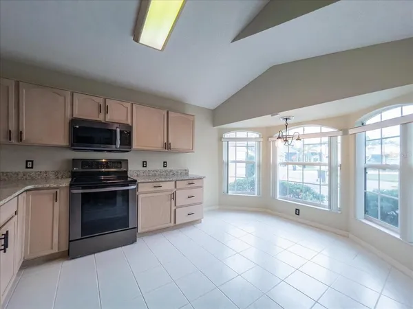 a large kitchen with stainless steel appliances granite countertop a stove a sink and a microwave