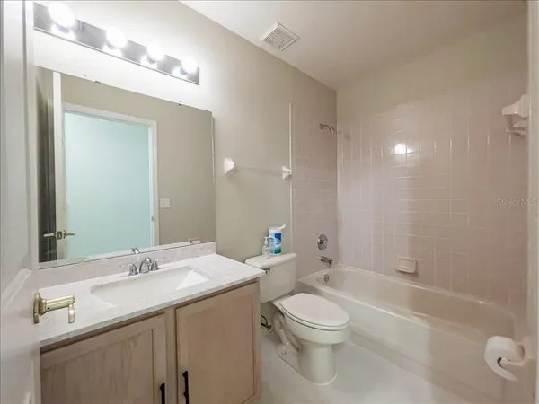 a bathroom with a toilet a sink a mirror a bathtub and vanity