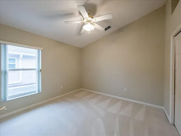 an empty room with windows and fan