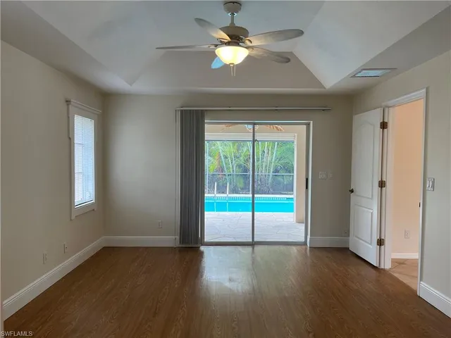 a view of an empty room with a window and wooden floor