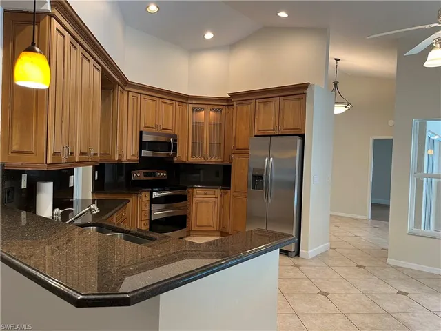 a kitchen with stainless steel appliances granite countertop a refrigerator a stove and a sink