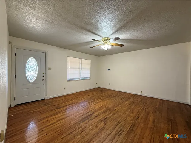 an empty room with wooden floor and chandelier fan