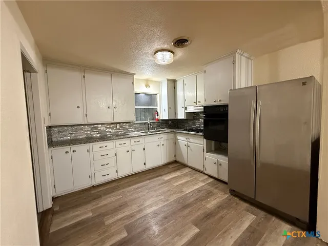 a kitchen with granite countertop white cabinets and white stainless steel appliances