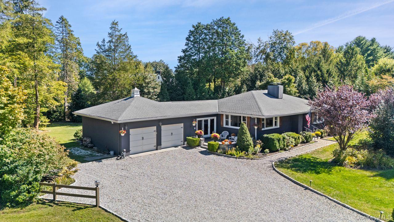 a view of a white house with a yard plants and large tree
