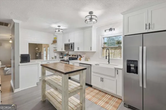 a kitchen with kitchen island white cabinets and refrigerator