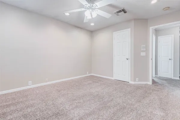 an empty room with a chandelier fan and closet area