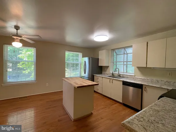 a kitchen with granite countertop wooden floors a sink and appliances