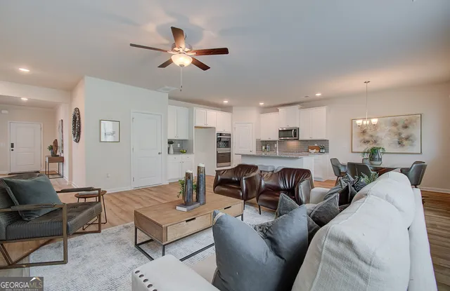 a living room with furniture kitchen view and a chandelier
