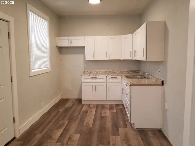 a view of a kitchen with wooden floor and electronic appliances