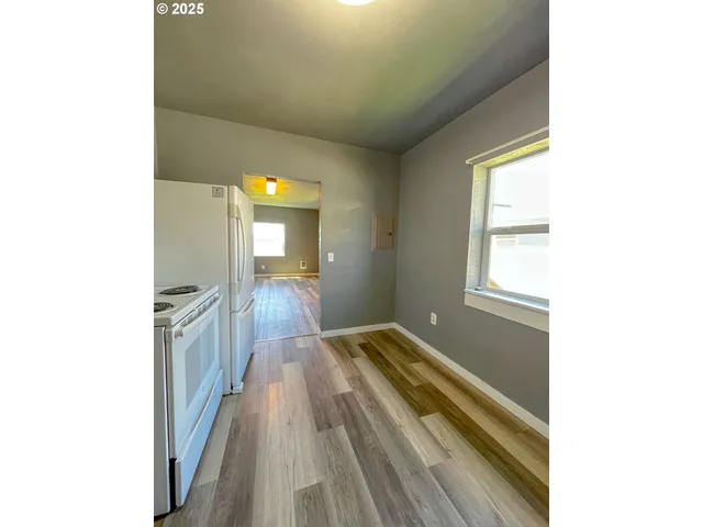 a view of a hallway with wooden floor and a bathroom