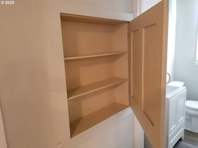 a walk in closet with wooden floor