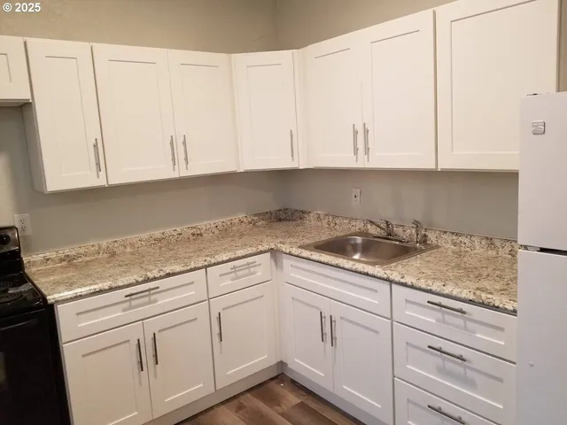 a kitchen with granite countertop white cabinets and a sink