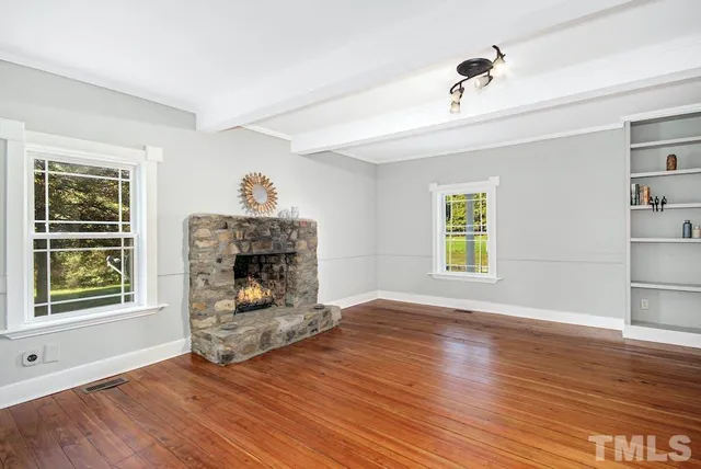 a view of empty room with wooden floor and fireplace