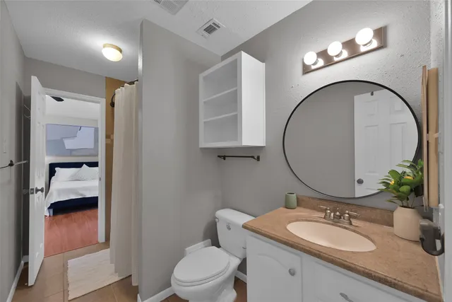 a bathroom with a granite countertop toilet a sink and a mirror