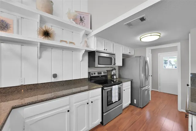 a kitchen with stainless steel appliances a stove a sink and cabinets