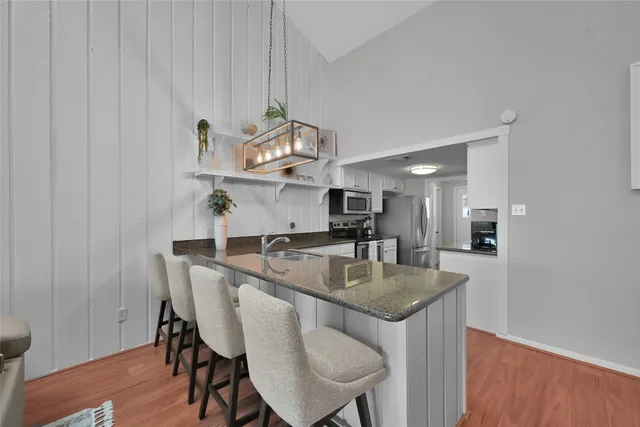 a kitchen with stainless steel appliances granite countertop a sink a stove a table and chairs